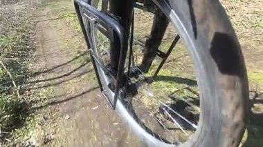 Bisiklet tekerleği toprak yolda gidiyor. Ağır çekim. Yan görünüm