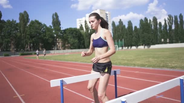 女运动员在跑道上 年轻的赛跑选手在体育场接受跨栏训练 慢动作 — 图库视频影像