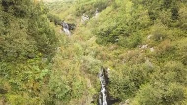 Havadan. Dağ tepelerindeki küçük şelalelerin üzerinden ağır çekim uçuş. Doğanın güzelliği