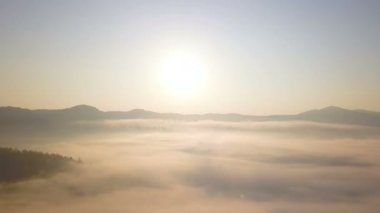4k .Aerial. Güneşin doğuşunda ya da batışında uç. Kızıl bulutlar ve güneş gökyüzünde, dağ bölgesinde.