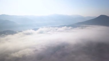 4k Havacılık manzarası. Dağlık bölgede bulutların üzerinde uçar, tepeler odunla. 