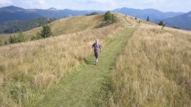 4k .Aerial. Yetişkin bir turist dağ yamacına çıkar., 
