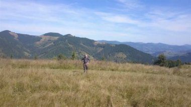 4k Aerial seyahat ekibi. Yetişkin turist dağ yamacında duruyor.. 