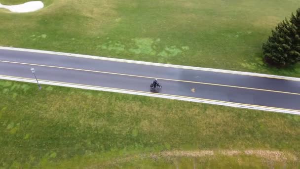 4K空中支援 独自骑自行车的人慢慢地走在田野间的路上 — 图库视频影像
