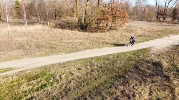 4K空撮 サイクリストの男は徐々にフィールドの間の未舗装の道路で行く — ストック動画
