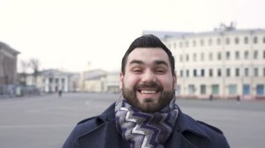 Keyfim yerinde. Sakallı, beyaz bir adam sokakta dikilip gülüyor. Portre 