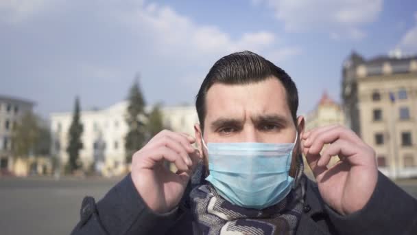 Stijlvolle Ernstig Bebaarde Blanke Man Doet Een Medisch Masker Lege — Stockvideo