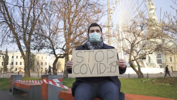 Homem Com Máscara Médica Senta Banco Com Cartaz Rua Cidade — Vídeo de Stock
