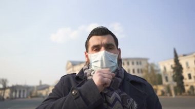 Boş şehir caddesinde tıbbi maskeli beyaz bir adam öksürüyor. Salgın ekibi, ağır çekim.