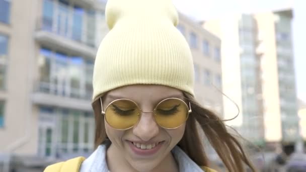 戴着黄色帽子和眼镜 面带微笑的年轻姑娘站在那里 对着镜头看 肖像画 — 图库视频影像