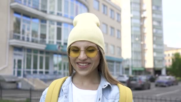 Mladá Pozitivní Dívka Žlutým Víčkem Brýlemi Stojí Místě Dívá Kamery — Stock video