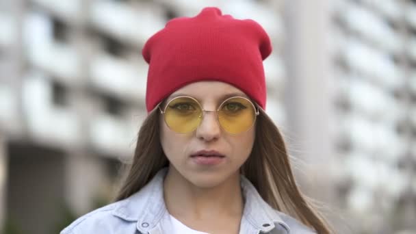 戴红帽戴眼镜的小女孩站在城市街道上 肖像画 — 图库视频影像