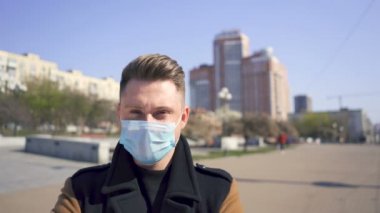 Beyaz adam boş şehir caddesinde tıbbi maske takıyor. Portreyi kapat