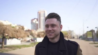 Genç, şık, pozitif, beyaz bir adam caddeye çıkıyor, kentin sabit portresi. 