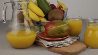 Bir bardak meyve suyu. Sarı ferahlatıcı yaz içkileri. Taze mango suyu, portakal suyu. Meyve sepeti masanın üstünde. Mutfakta taze meyve ve meyve suyu var. Vejetaryen yemeği. Vitamin içeceği. Muz, kivi, limon.