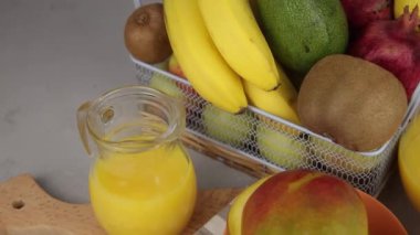 Bir bardak meyve suyu. Sarı ferahlatıcı yaz içkileri. Taze mango suyu, portakal suyu. Meyve sepeti masanın üstünde. Mutfakta taze meyve ve meyve suyu var. Vejetaryen yemeği. Vitamin içeceği. Muz, kivi, limon.