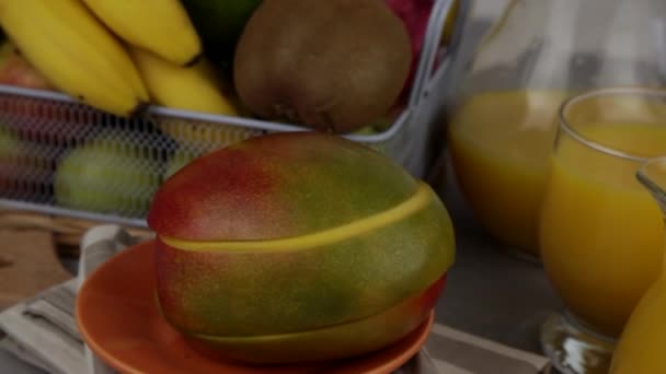 一杯果汁 黄色令人神清气爽的夏季饮料 新鲜的芒果汁橙汁桌上的果篮 厨房里新鲜的水果和果汁 维生素饮料 猕猴桃 — 图库视频影像