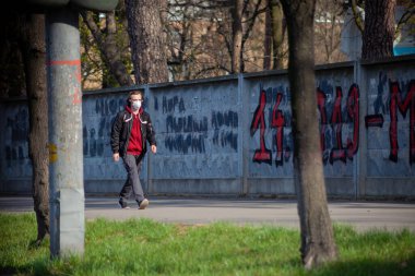 Kyiv, Ukrayna - 11 Nisan 2020: Koruyucu maskeli bir adam şehirde yürüyor. Coronavirüs salgını sırasında şehrin sokakları. COVID-19