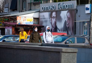 Kyiv, Ukrayna - 11 Nisan 2020: Koruyucu maskeli insanlar şehirde dolaşıyor. Coronavirüs salgını sırasında şehrin sokakları. Solunum cihazındaki adam ve kız ve tıbbi maske..
