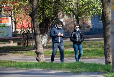Kyiv, Ukrayna - 11 Nisan 2020: Koruyucu maskeli insanlar şehirde yürüyor. Coronavirüs salgını sırasında şehrin sokakları. Solunum cihazı ve tıbbi maske. Karantina sırasında kadın ve erkek sokakta..