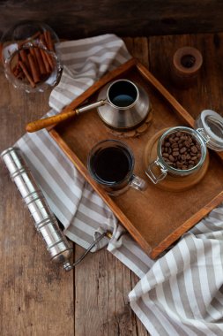 Tahta tepside bir fincan kahve. Türk ve kahve çekirdekleri. Kahvaltıyı evde yap. Bardakta içkiyle sakin bir hayat. Tahta masadaki çizgili masa örtüsü..
