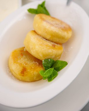 Yuvarlak peynirli kekler. Beyaz tabakta ev yapımı yemek servisi. Kahvaltıda naneli cheesecake, üç porsiyon. Yüksek kalsiyum iştah açıcı sağlıklı yiyecekler.