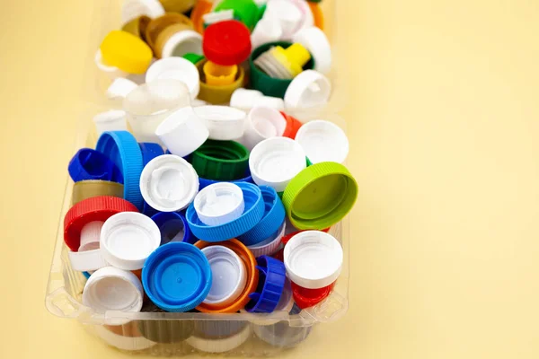Sort plastic bottle caps. Recycling. Zero waste. Yellow background with place for text. Eco friendly.