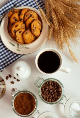 Beyaz kahve ve çikolatalı yuvarlak kurabiyeler. Kahvaltınız masada. Evde yemek var. Durgun hayat. Kahve ve kahve çekirdekleri. Canlandırıcı bir içecek..