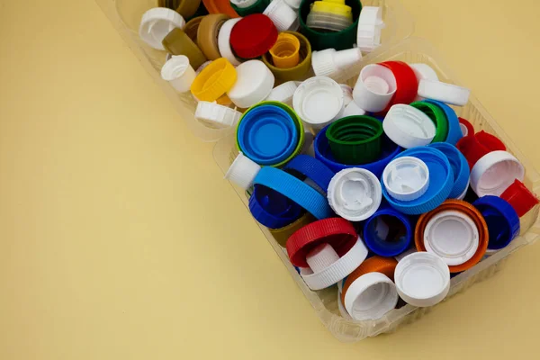 Sort plastic bottle caps. Recycling. Zero waste. Yellow background with place for text. Eco friendly.