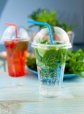 Mojito ve Lemonade yaz aylarında plastik bardakta pipetle soğuk bir şeyler içerler. Naneli, limonlu, limonlu, buzlu. Barda servis yap..