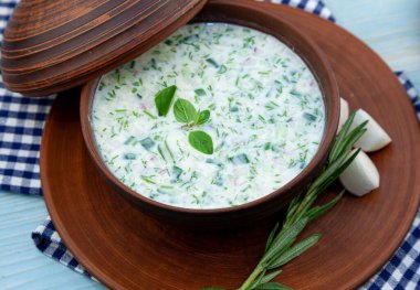 Okroshka - soğuk yaz çorbası. Taze salatalık, turp, patates ve sosisli soğuk çorba. Geleneksel Rus yemekleri. Okroshka kefir ve biberiyeli kil tabakta kapaklı. Dill, maydanoz, haşlanmış yumurta..
