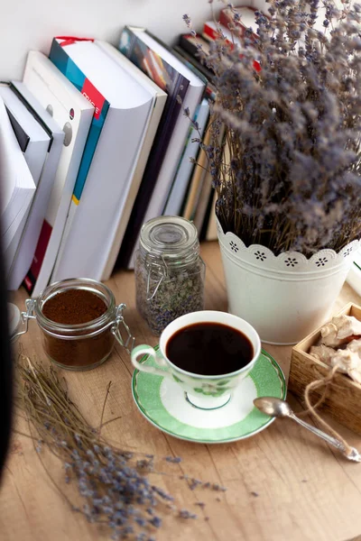 Books, coffee and a bouquet of dried lavender. Still life on the table. Breakfast top view. A cup of invigorating drink. Home cozy background. Ground coffee beans in a jar. Dried flowers.