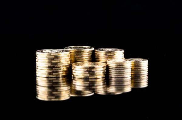 Mince zlaté peníze stohování na tmavém pozadí — Stock fotografie