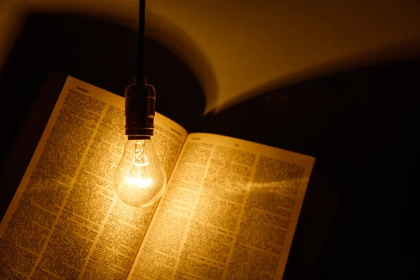 Electric bulb illuminating a book — Stock Photo, Image