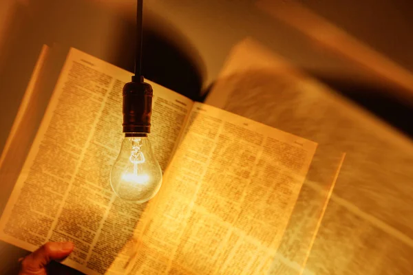 Lâmpada elétrica iluminando um livro — Fotografia de Stock