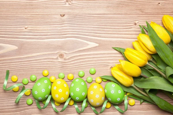 Uova di Pasqua e tulipani su sfondo di legno. — Foto Stock