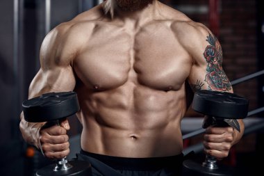 Atlet kaslı vücut geliştirmeci dumbbells ile.