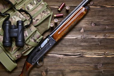 Hunting rifle and ammunition on a wooden background. clipart