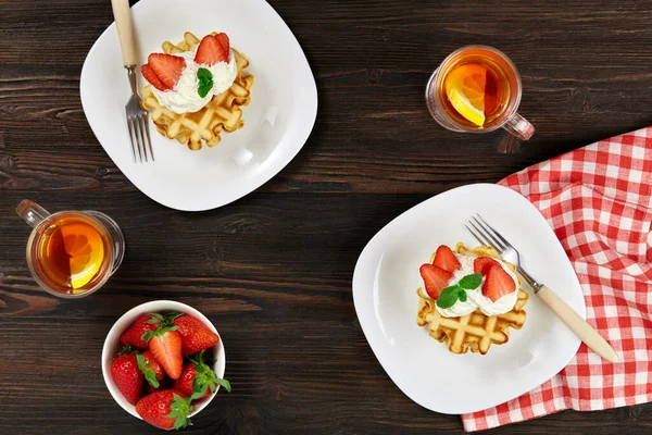 美味的早餐比利时维也纳华夫饼 装饰有奶油和草莓 茶和深色木制乡村背景的方块餐巾 — 图库照片