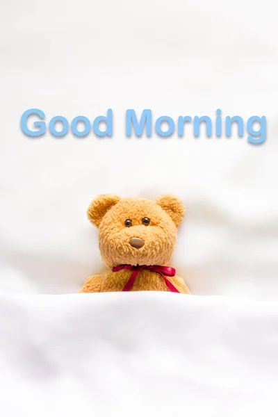 Teddybär liegt im weißen Bett mit der Botschaft "Guten Morgen " — Stockfoto