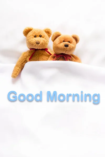 Osito de peluche acostado en la cama blanca con el mensaje "Buenos días  " — Foto de Stock