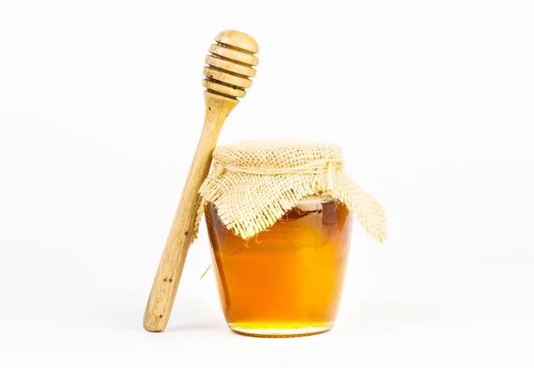 Glass jar full of honey wooden honey dipper on white background — Stock Photo, Image