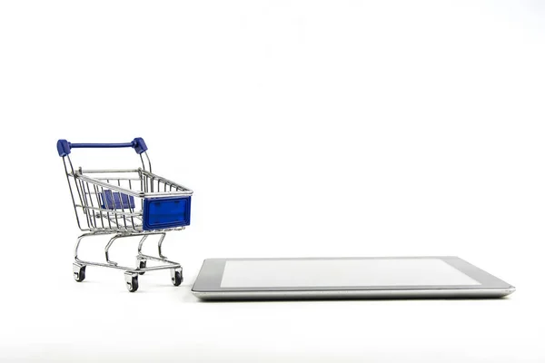 Carrinho de compras com tablet no fundo branco, significa fazer compras em — Fotografia de Stock