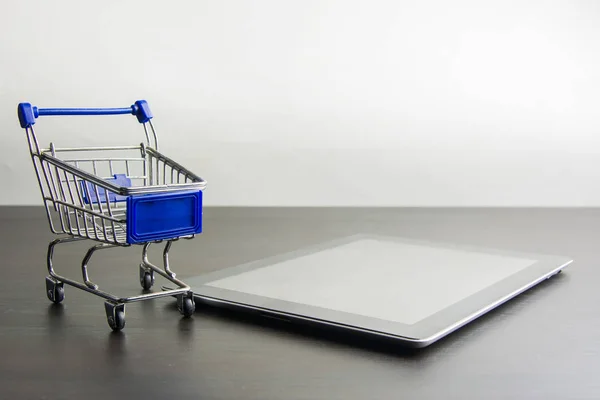 Tablet com carrinho de compras em madeira, meios de compras on-line — Fotografia de Stock