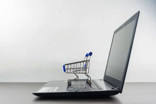 Computer notebook blank screen with shopping cart on wood table