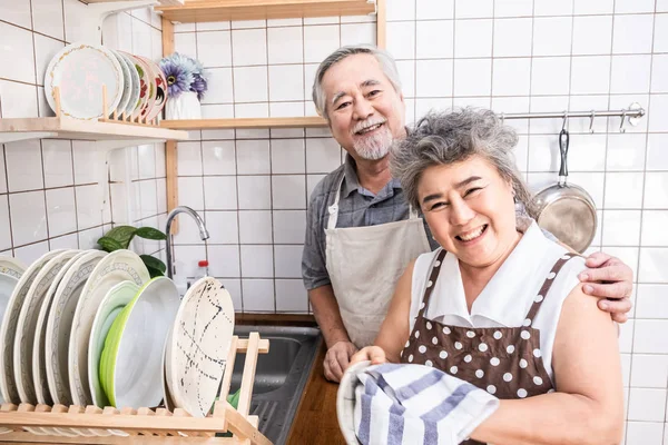 Pareja mayor en la cocina y sonriendo mientras cocinan juntos — Foto de Stock