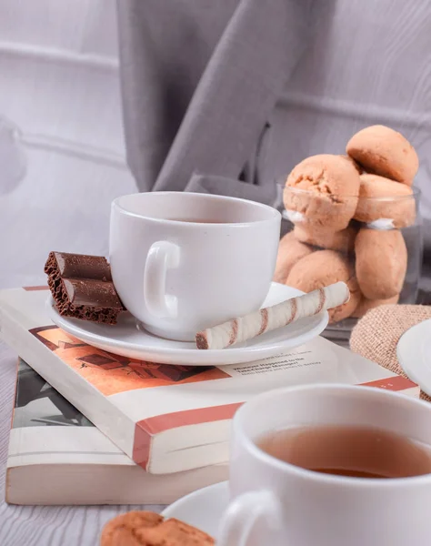 Buch, süße Snacks und Tee auf dem Tisch — Stockfoto