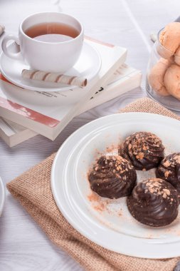 Kitap, bir fincan çay ve arka planda çikolata.
