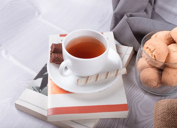 Snacks sucrés, tasse de thé et chocolat et livre sur fond clair — Photo