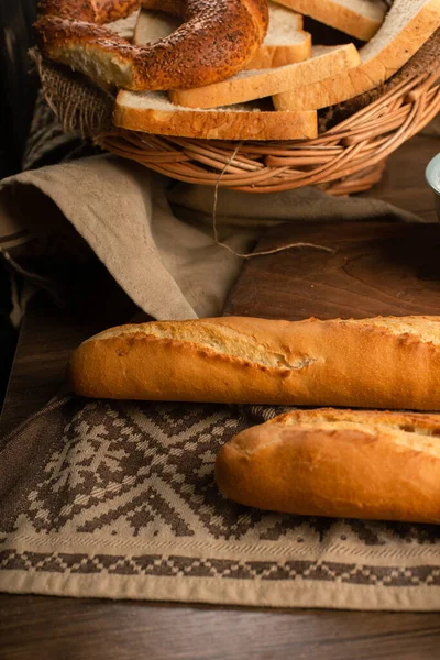 Французький багет зі шматочками хліба і бубликів у кошику. — стокове фото